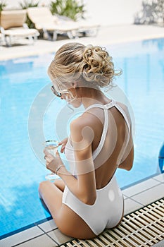 Fashionable and beautiful model blonde girl with body in stylish sunglasses and white swimsuit with naked back