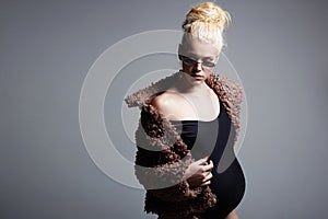 Fashionable beautiful pregnant blond woman in fur and sunglasses