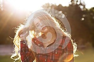 Fashionable blonde model in checkered dress posing in rays of sun