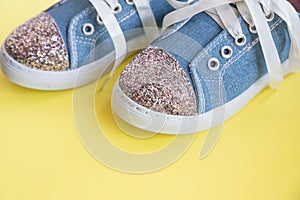 Fashionable blue sneakers for girls isolated on yellow background. Pair of trendy kids sports shoes.Trandy denim