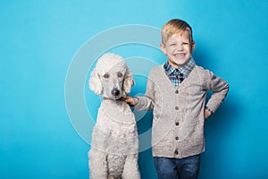 Fashionable boy with dog. Friendship. Pets. Studio portrait over blue background