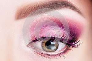 Fashionable bright eye makeup close-up. Female eye with violet shadows and false eyelashes
