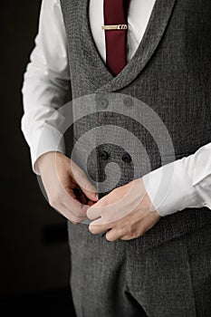 Fashionable business man wearing a tie fastening a button on a gray stylish jacket, close-up.Men fashion concept