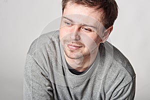 Fashionable casual happy young man with light beard, on gray background