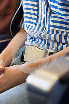 Female passenger with seat belt fastened while sitting on airplane for safe flight.