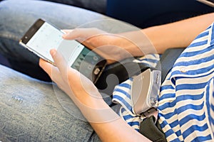 Female passenger with seat belt fastened switching mobile phone to flight mode while sitting on airplane for safe flight