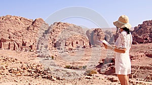 Fashionable caucasian woman tourist, read map, plan exploring the sights of the ancient, fabulous city of Petra in Jordan.