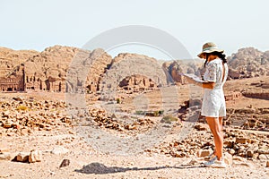 Fashionable caucasian woman tourist, read map, plan exploring the sights of the ancient, fabulous city of Petra in Jordan.