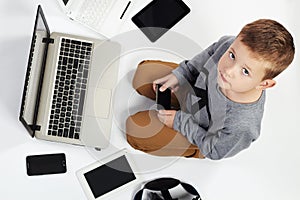 Fashionable child with computers, tablets, phones, gadgets around