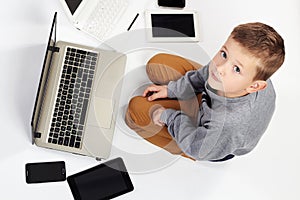 Fashionable child with computers, tablets, phones, gadgets around