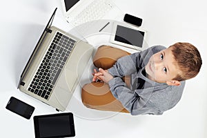 Fashionable child with computers, tablets, phones, gadgets around