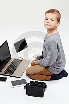 Fashionable child with computers, tablets, phones, gadgets around