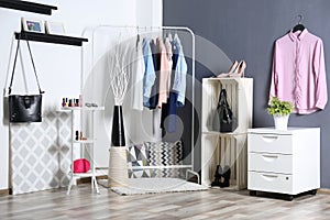 Fashionable clothes hanging on rack