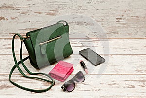 Fashionable concept: eyeshadows, handbag, glasses, lipstick, wallet on a wooden background. top view