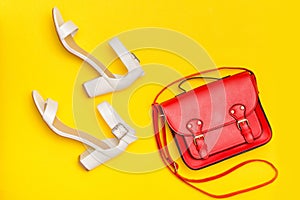 Fashionable concept. Red handbag and white shoes. Yellow background, top view