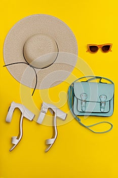 Fashionable concept. Women`s beach hat, handbag, white shoes. Yellow background, top view