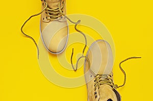 Fashionable concept. Yellow men`s work boots from natural nubuck leather on bright yellow background top view flat lay with copy