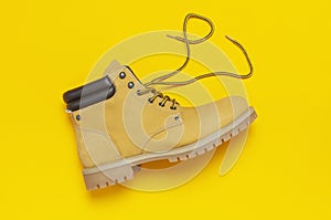 Fashionable concept. Yellow men`s work boots from natural nubuck leather on bright yellow background top view flat lay with copy