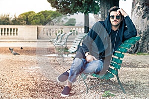 Fashionable cool young man with sunglasses relaxing on a bench