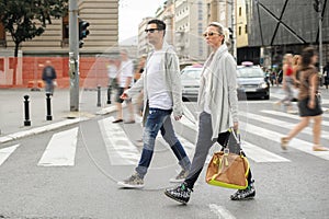 Fashionable couple crossing road at pedestrian zebra crossing