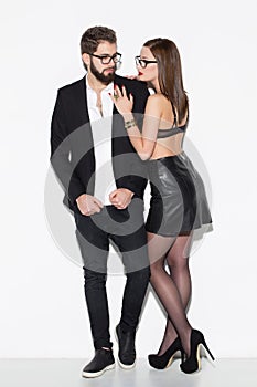 Fashionable couple in eyeglasses posing at white wall