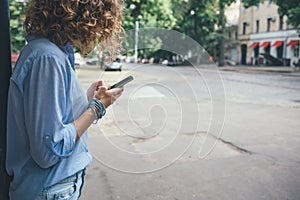 Fashionable curly young woman standing on the sidewalk