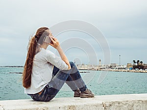Fashionable, cute woman with a phone on the background of the sea