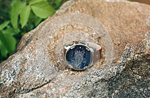 Fashionable elegant men`s watch lying outdoors on the stone. Stylish accessories in the nature forest