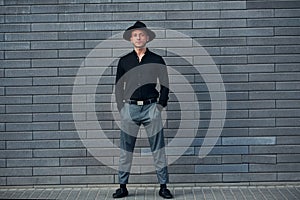 Fashionable elegant man standing outdoors against grey wall