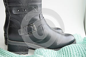 Fashionable and elegant women`s winter leather shoes on white background, next green knitted jumper