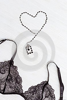 Fashionable female lace bra and figure of heart on wooden background