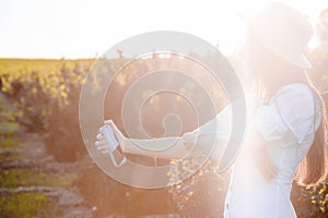 Fashionable female making selfie or video call on smartphone in countryside. Portrait of beautiful happy Caucasian girl