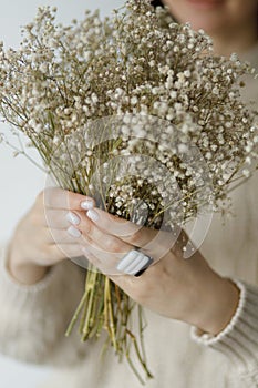 Fashionable female in sweater with unusual fused glass accessories and white manicure. Beauty. Care