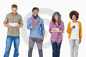 Fashionable friends standing in a row using media devices