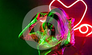 Fashionable girl dancing in night club. Cheerful African American woman dancing among the bright neon lights. Party