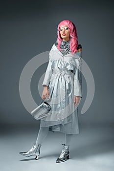 fashionable girl in pink wig and eyeglasses posing with watering can