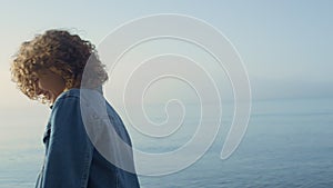 Fashionable girl posing at seashore. Smiling woman turning around on ocean beach