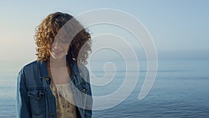 Fashionable girl posing at seashore. Smiling woman turning around on ocean beach