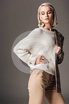 fashionable girl posing in white sweater and tweed jacket on one shoulder