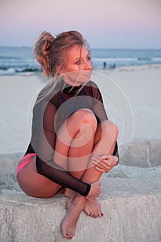 Fashionable girl is relaxing on the beach at sunset