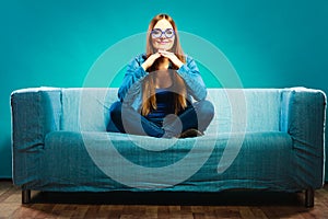 Fashionable girl wearing denim sitting on couch.