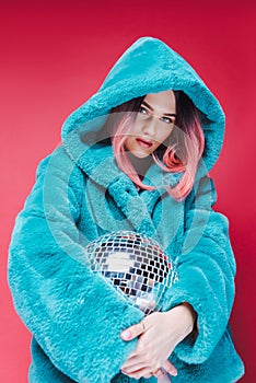 fashionable glamour girl posing in blue fur coat with disco ball,