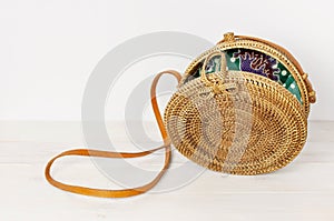 Fashionable handmade natural organic rattan bag on light wooden background. Ladies bag made of natural material. Ecobags from Bali