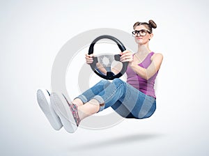 Fashionable happy young woman in glasses with car steering wheel. Girl auto driving concept
