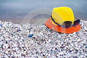 Fashionable hat with glasses are on the sea shells. Concept of tourist recreation on the sea beach