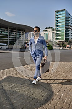 Trendy Indian businessman walking in city on daily work commute photo