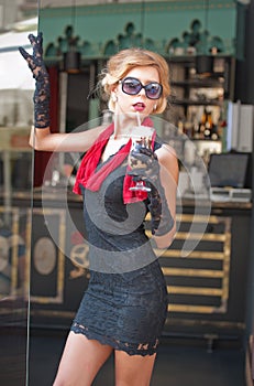 Fashionable lady with short black lace dress and red scarf and high heels, outdoor shot . Young attractive short haired blonde