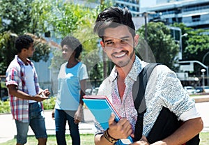 Fashionable latin male student outdoor on campus with friends