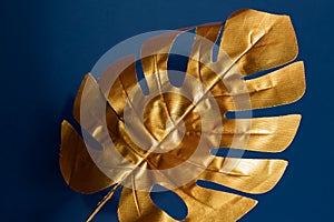 Fashionable luxuary blue background with gold monstera leaf