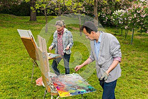 Fashionable male and female mixing paint with a paletteknife during an art class